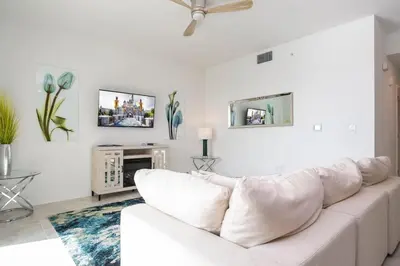 a white living room with a white couch and a tv at 3191 Unit 207 Stunning apartment in Kissimmee