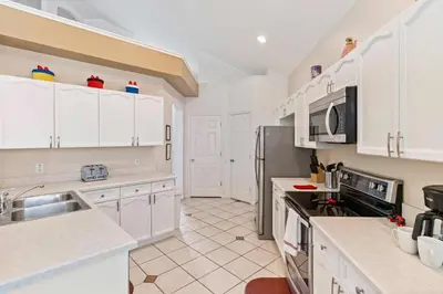 a kitchen with white cabinets and a stainless steel refrigerator at 8213 Fan Palm Way in Kissimmee
