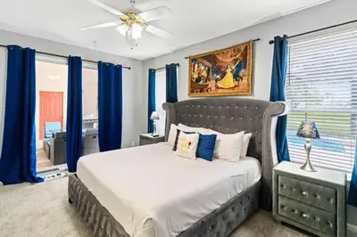 a bedroom with a large bed with blue curtains at 8213 Fan Palm Way in Kissimmee