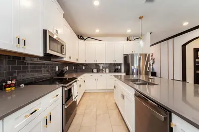 a kitchen with white cabinets and stainless steel appliances at New Beautiful 7 br w pool games theme rooms in Kissimmee