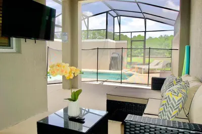a living room with a couch and a table and a pool at Cozy & Magical place sleeps 12/10 min from Disney in Kissimmee