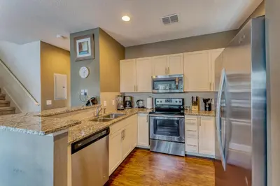 a kitchen with white cabinets and stainless steel appliances at Happy Holiday Hideaway G in Kissimmee
