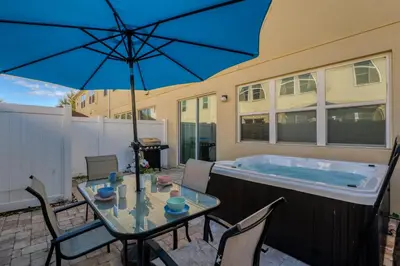 a patio with a table with an umbrella and a tub at Making Memories G in Kissimmee