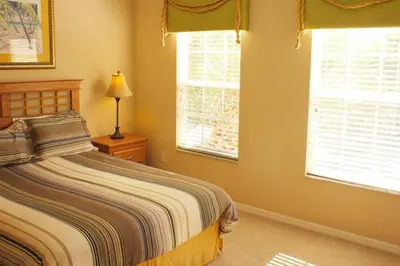 a bedroom with a bed and two windows at 4 bedroom townhouse Sleeps 8 Coral Cay in Kissimmee