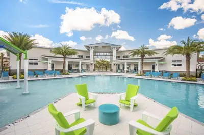 a swimming pool with chairs and a building at 6 bedrooms pool home Gated resort Veranda Palms in Kissimmee