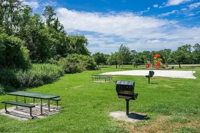 a park with two picnic tables and a playground at LB4707AW 3 Bedroom Villa with pool and game room in Kissimmee