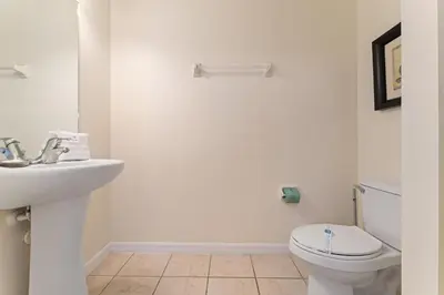 a white bathroom with a toilet and a sink at Pool Townhouse near to Disney - Bella Vida Resort in Kissimmee