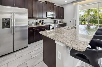 a kitchen with a stainless steel refrigerator and a counter at Modern 5 BDR Family Themed Home with Harry Potter Games Room and Free Pool Heat in Orlando