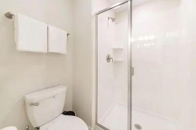 a white bathroom with a shower and a toilet at Magic villa with themed bedrooms and private pool in Kissimmee