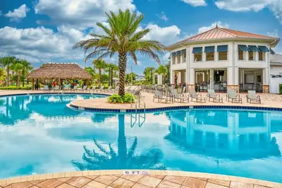 a resort pool with chairs and a palm tree at Magic villa with themed bedrooms and private pool in Kissimmee