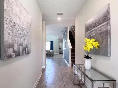 a hallway with a vase of yellow flowers on a table at 5 Bed 5 Bath South Facing Pool Home Storey Lake home in Kissimmee