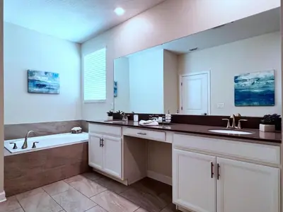 a bathroom with two sinks and a large mirror at 5 Bed 5 Bath South Facing Pool Home Storey Lake home in Kissimmee