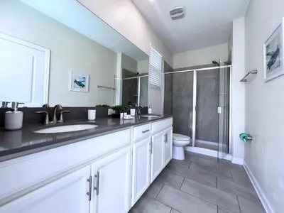 a white bathroom with a sink and a shower at 5 Bed 5 Bath South Facing Pool Home Storey Lake home in Kissimmee