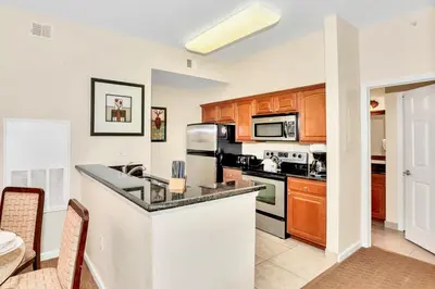 a kitchen with wooden cabinets and a counter top at 2BR Resort Suite - Fountain View Private Balcony in Kissimmee