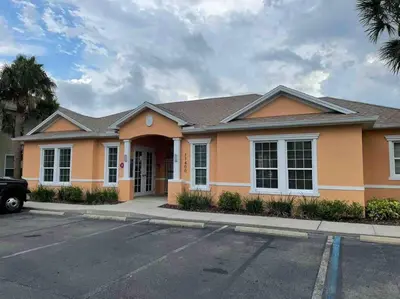 a orange house with a car parked in a parking lot at Like home, but better in Orlando