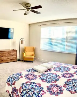 a bedroom with a bed and a fan and a chair at Like home, but better in Orlando