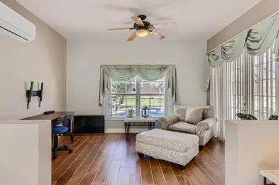 a living room with a ceiling fan and a chair and a desk at The Marvel Mansion 5BR Pool Home Near Disney World in Orlando
