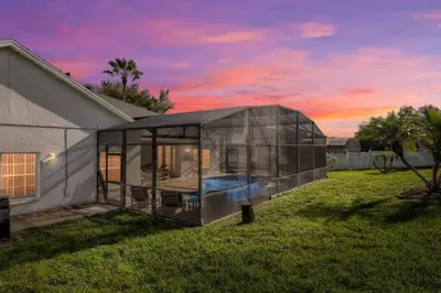 a glass house in a yard next to a house at The Marvel Mansion 5BR Pool Home Near Disney World in Orlando