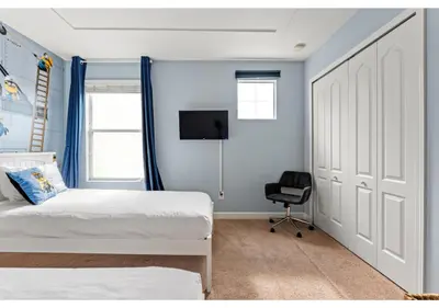 a bedroom with two beds and a door with a chair at Lakefront 5BR Resort Pool Home Near Disney World in Kissimmee