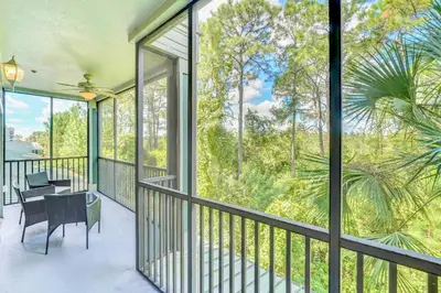 a screened in porch with a table and chairs and windows at Near Disney - 3BR Condo - Pool and Games in Orlando