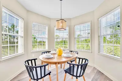 a dining room with a table and chairs and windows at 3BR Condo - Pool Sauna - Near Disney in Orlando