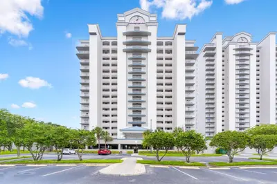 a large white building with trees in front of it at Blue Heron Beach Resort in Orlando