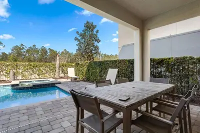 a patio with a wooden table and chairs next to a pool at Multiple Family Homes - 23 Rooms PoolsSpas in Orlando