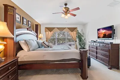 a bedroom with a bed with a ceiling fan and a dresser at The Pink House at Windsor Hills in Orlando