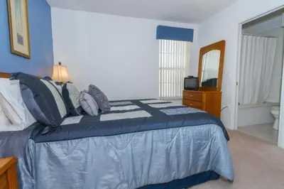 a bedroom with a bed with a blue comforter and a mirror at Home With A View! in Orlando