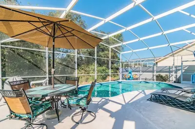 a patio with a table with an umbrella and a pool at THIS IS PARADISE FOUND! Private In-Ground Pool Home, Views, Near Dis, NO Steps, LOW Rates! in Kissimmee