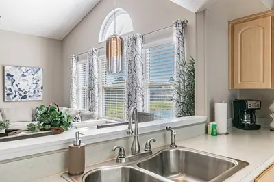 a kitchen with a sink and two windows at THIS IS PARADISE FOUND! Private In-Ground Pool Home, Views, Near Dis, NO Steps, LOW Rates! in Kissimmee