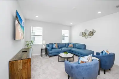 a living room with a blue couch and chairs at Near Disney - 12BR Home - Private Pool and Hot Tub in Kissimmee