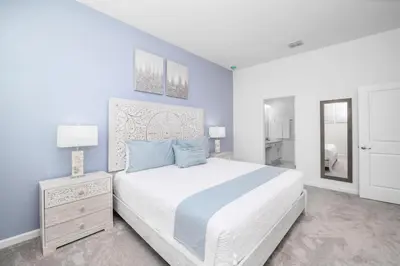 a white bedroom with a large bed and a mirror at Near Disney - 12BR Home - Private Pool and Hot Tub in Kissimmee