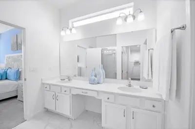 a white bathroom with a sink and a mirror at Near Disney - 12BR Home - Private Pool and Hot Tub in Kissimmee