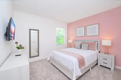 a bedroom with a white bed and a pink wall at Near Disney - 12BR Home - Private Pool and Hot Tub in Kissimmee