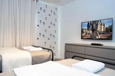 a room with two beds and a tv on a wall at Brand new fantastic home at Storey lake (SL4447) in Kissimmee