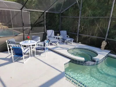 a patio with chairs and a table next to a pool at Cozy Private Home at Terra Verde Resort, South Facing Pool Spa, Near Disney, SeaWorld in Kissimmee
