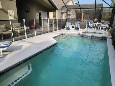 a large swimming pool with chairs and a table at Cozy Private Home at Terra Verde Resort, South Facing Pool Spa, Near Disney, SeaWorld in Kissimmee
