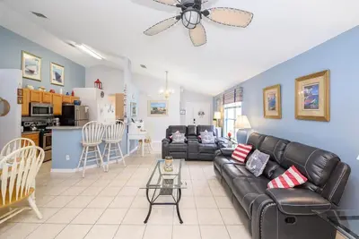 a living room with a black leather couch and a kitchen at Cozy Private Home at Terra Verde Resort, South Facing Pool Spa, Near Disney, SeaWorld in Kissimmee