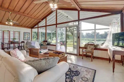 a living room with white furniture and glass windows at Near Kayak Launch Riverfront Home in Sanford! in Sanford