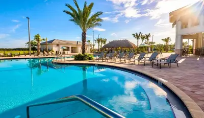 a swimming pool at a resort with chairs and palm trees at 4BR Townhouse with Private Pool near Disney in Kissimmee