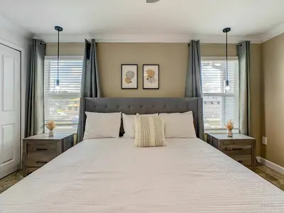 a bedroom with a large bed with two windows at 4BR Townhouse with Private Pool near Disney in Kissimmee