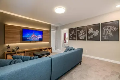 a living room with a blue couch and a flat screen tv at 7988 Magical 5BD Home Perfect Disney Retreat in Kissimmee