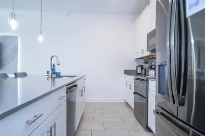 a kitchen with white cabinets and a stainless steel refrigerator at 2941 Modern Four Bedroom Locate at Storey Lake in Kissimmee