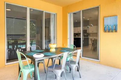 a dining room table and chairs in a room with windows at Family Retreat 6BR Villa with Private Pool, Spa & Theater near Disney in Kissimmee