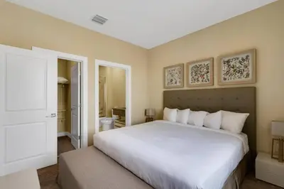 a bedroom with a large white bed and a bathroom at Luxury Townhouse located NEXT to DISNEY ORLANDO in Orlando