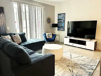 a living room with a couch and a flat screen tv at Gorgeous Condo Close to Disney w Private Pool BBQ - Themed Bedrooms Walk To Clubhouse in Kissimmee