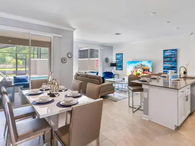 a kitchen and living room with a table and chairs at Gorgeous Condo Close to Disney w Private Pool BBQ - Themed Bedrooms Walk To Clubhouse in Kissimmee