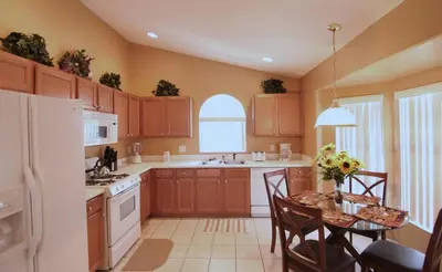 a kitchen with wooden cabinets and a table with chairs at Emma Castle - private fenced home 3 miles to Disney in Kissimmee