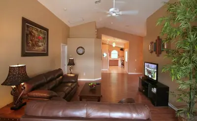 a living room with a leather couch and a television at Emma Castle - private fenced home 3 miles to Disney in Kissimmee